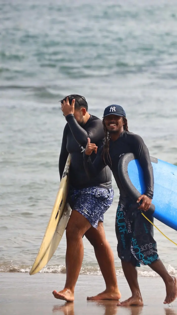 Gervas walking out of the water with a student after a surf lesson